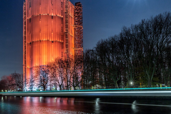 Nachtaufnahme mit orange angeleuchtetem Gasometer