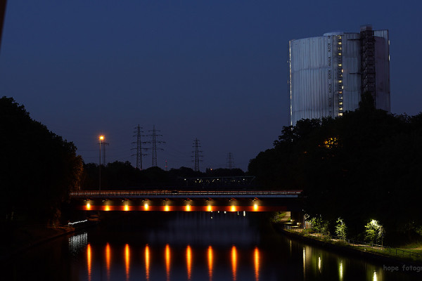 Nachtaufnahme des Gasometers mit Rhein-Herne-Kanal im Vordergrund
