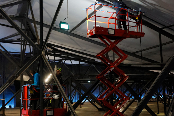 Drei Arbeiter und zwei Hubwagen im Einsatz.