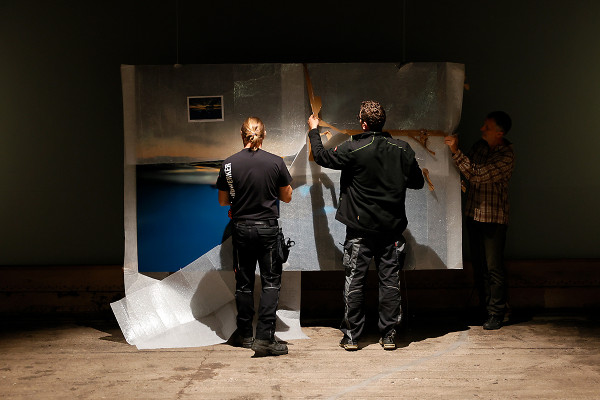 Zwei Mitarbeiter entpacken ein großformatiges Foto