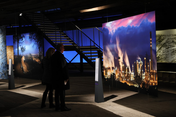 Zwei Personen betrachten ein großformatiges Foto mit einer Industrieklulisse