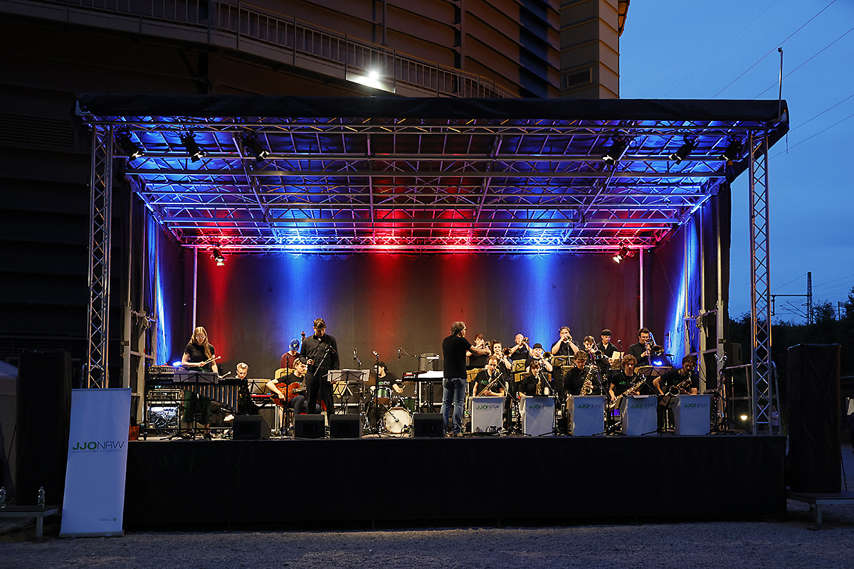 Übersichtsaufnahme des JJO NRW bei einem Auftritt auf einer Bühne vor dem Gasometer Oberhausen