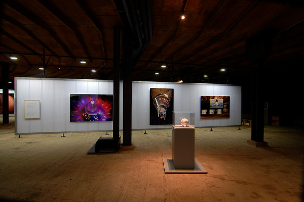 Ein Fußball liegt in einer Vitrine im Vordergrund, im Hintergrund sind großformatige Fotos zu sehen