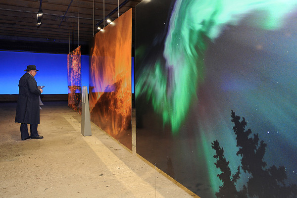 Besucher betrachtet großformatige Fotografien