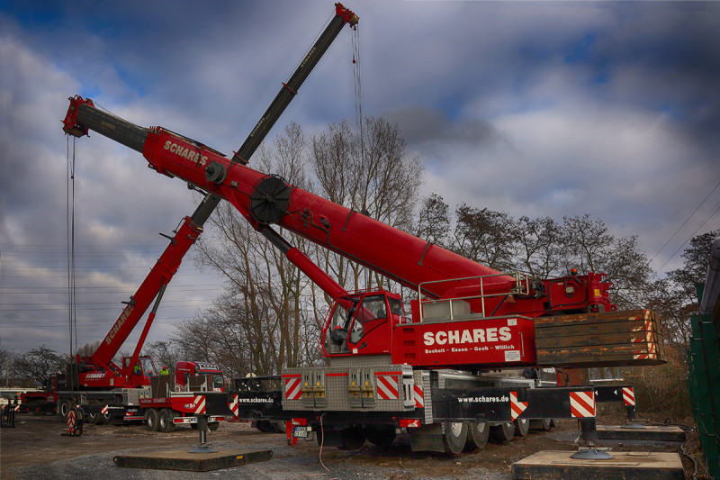 Zwei Autokräne auf stehen der Rückseite des Gasometers.