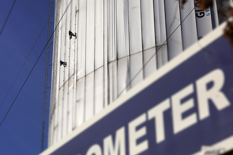 Gasometer Haltestellenschild mit verhülltem Gasometer und Industriekletterern im Hintergrund