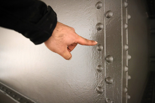 Ein Finger zeigt auf die Außenhülle des Gasometers mit der zweiten, grauen Zwischenschicht